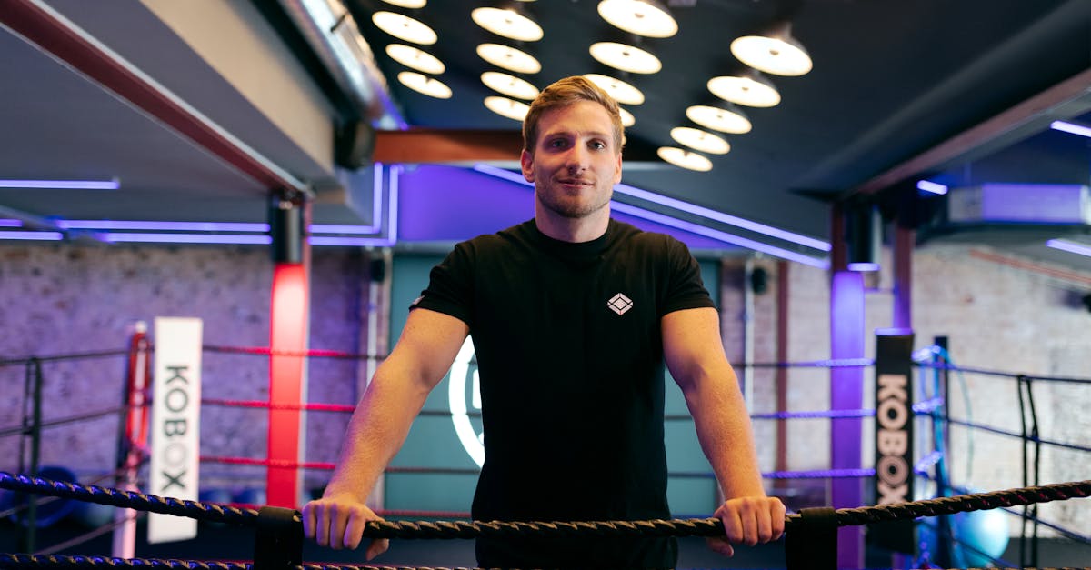 a male trainer stands confidently in a modern boxing gym with vibrant lighting