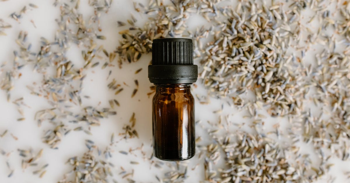 a close up of an amber bottle with lavender seeds on a white background top view